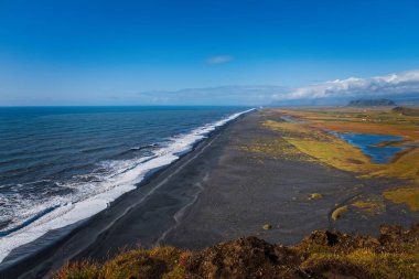 Reynisfjara Black Sand Beach, İzlanda 'nın güney kıyısında güneşli bir günde bir uçurumdan görülen Vik i Myrdal köyünün yakınlarında bulundu. Eylül 2019