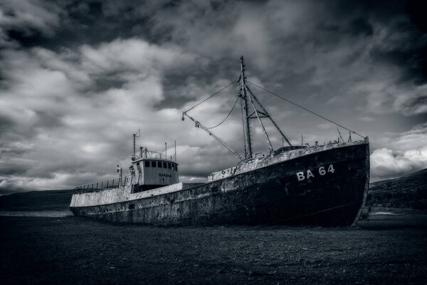 Старое ржавое стальное кораблекрушение находится на исландском пляже. Черно-белое изображение. Сентябрь 2019
