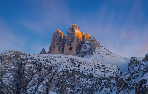 Colorful sunset sunset in Dolomites mountains, three peaks of Tre Cime di Lavaredo in snowy and cloudy background. Italy, Europe. January 2020