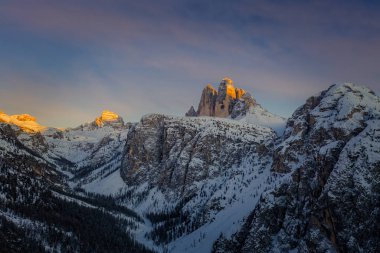 Dolomites dağlarında gün batımı, karlı ve bulutlu arka planda Tre Cime di Lavaredo 'nun üç zirvesi. İtalya, Avrupa. Ocak 2020
