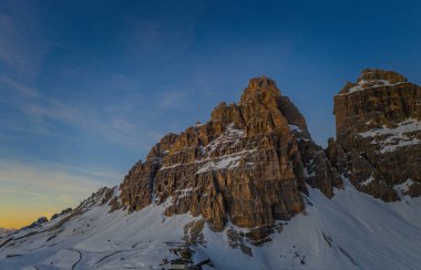 Dolomites dağlarında gün batımı, karlı ve bulutlu arka planda Tre Cime di Lavaredo 'nun üç zirvesi. İtalya, Avrupa. Ocak 2020