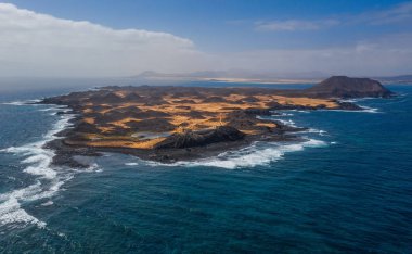 İspanya 'nın Kanarya Adaları, Fuerteventura sahilinin sadece 2 kilometre açığındaki ıssız bir ada olan Isla de Lobos' un çarpıcı yüksek açılı panoramik hava aracı görüntüsü. Ekim 2019