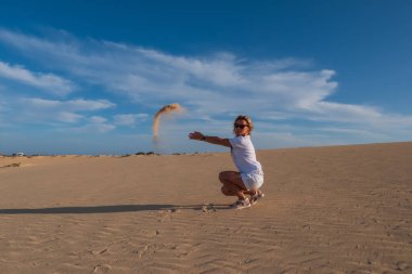 Genç kadın kum tepelerine kum atıyor Corralejo, Fuerteventura. Kanarya Adaları, İspanya. Ekim 2019