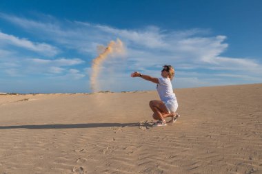 Genç kadın kum tepelerine kum atıyor Corralejo, Fuerteventura. Kanarya Adaları, İspanya. Ekim 2019