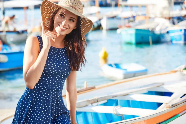 Güzel kadın teknede plajda otururken hasır şapkalı. Summe