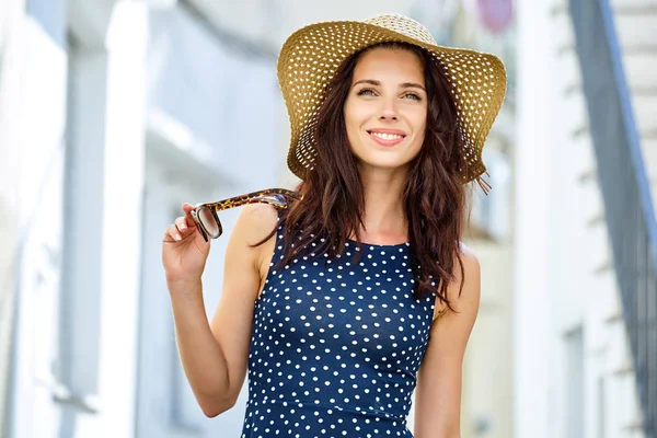 Beautiful young woman in a dress and a straw hat walks through t — Stock Photo, Image