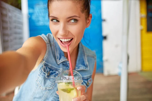 Lovely young smiling woman drinking lemonade and make a selfie. — Stock Photo, Image