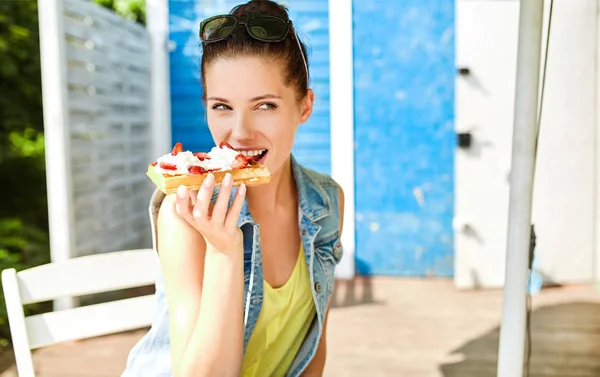 Girl eats waffles with whipped cream and strawberries — Stock Photo, Image