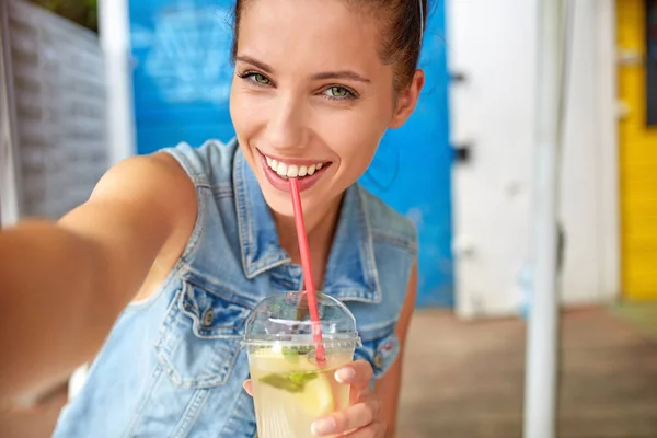 Lovely young smiling woman drinking lemonade and make a selfie. — Stock Photo, Image
