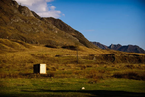在阿尔泰山脉背景下的田野里孤零零地建筑 — 图库照片