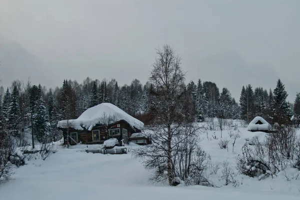 Houten huis in de winter met de rook uit de schoorsteen — Stockfoto