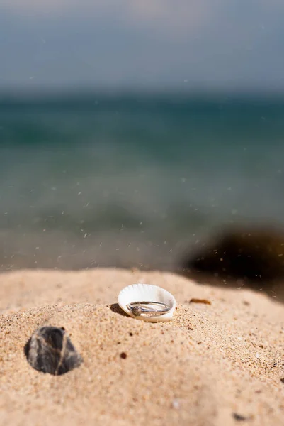 Anel de noivado com diamante na casca na areia — Fotografia de Stock