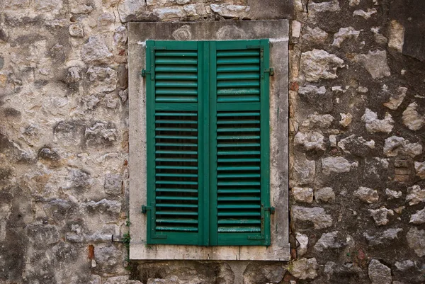 Uma janela fechada por persianas de madeira-blinds cor verde — Fotografia de Stock