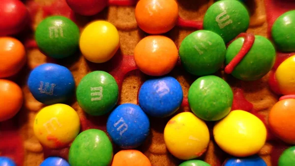 Pequenos chocolates coloridos no telhado de uma casa de gengibre caseira — Fotografia de Stock