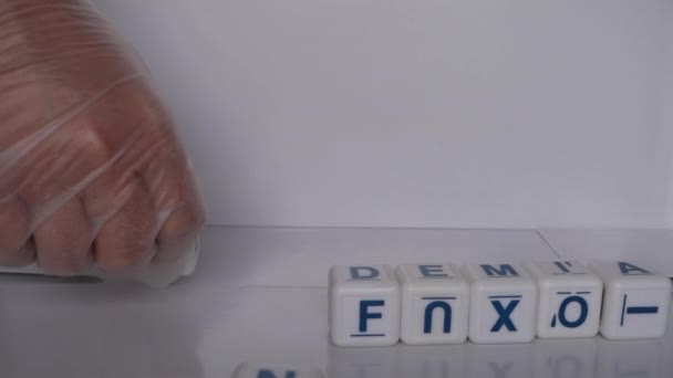 用手拿着手套 用白色骰子拼凑 大流行病 这个词的小录像 — 图库视频影像