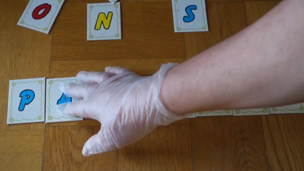 Kleines Video, das die Hände mit Handschuhen zeigt, aus denen sich der Satz Pandemie stay home mit farbigen Buchstaben zusammensetzt