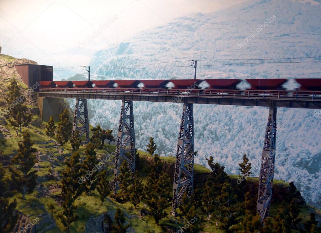 a freight train runs on the tracks of a railway bridge that crosses the valley between the mountains