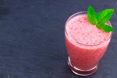 Çilek suyu bir fincan nane ile bir oryantal renkli arka plan üzerinde bırakır