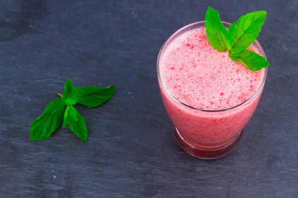 Çilek suyu bir fincan nane ile bir oryantal renkli arka plan üzerinde bırakır