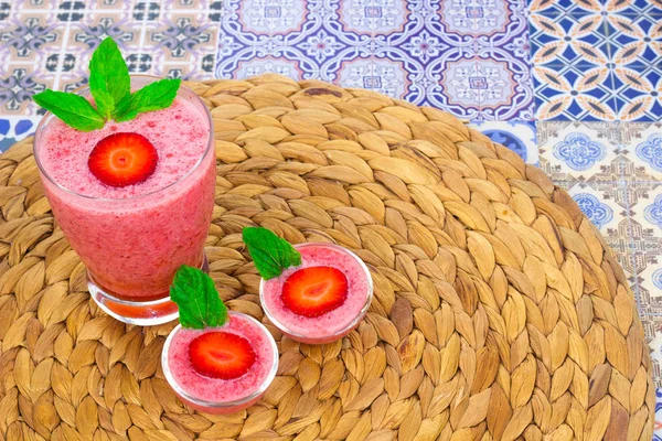 Une tasse de jus de fraise avec des feuilles de menthe sur un fond coloré oriental — Photo