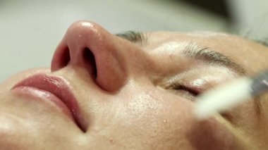 A woman is preparing for a laser rejuvenation procedure in the salon. A cosmetologist-dermatologist completes the photorejuvenation procedure. Shooting is from different angles