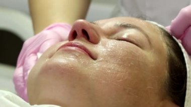 A woman is preparing for a laser rejuvenation procedure in the salon. A cosmetologist-dermatologist completes the photorejuvenation procedure. Shooting is from different angles