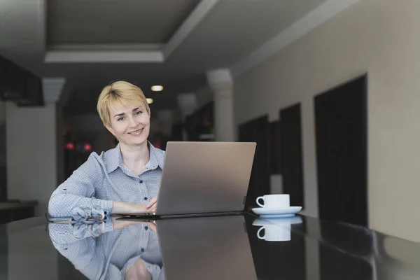 Elegant woman blonde is using laptop in cafe. Blogger job concept