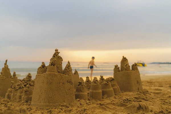 Deniz kıyısındaki güzel kumdan kale. Çocuklar tarafından inşa edilen kum kalesi yakın ve büyük. Deniz kıyısındaki çocuk arka planda.