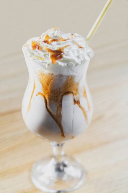 Sütlü süt karışımı, çırpılmış krema ve karamelli cam kaplama, ahşap arka planda çevre dostu bambu kamışı..