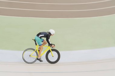 Bisikletli genç sporcu bisiklet yarışına katılmak için atletizm kıyafetleriyle bisiklet pistinde.
