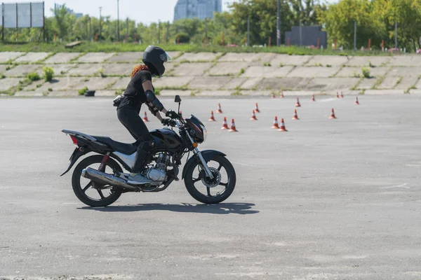 Motor pistinde bisiklet sürmeyi öğrenen bir kız. Motosikletli bir motorcu..