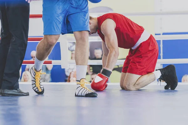 Knockout in boxing and taste defeat. Boxer kneeling with his head bowed. Horizontal image.