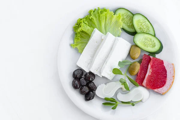 Suluguni und feta griechischer Käse auf weißem Teller mit frischem Gemüse auf weißem Hintergrund, Makro- und Kopierraum. leichtes, gesundes Frühstück. Natürliches Ernährungskonzept — Stockfoto