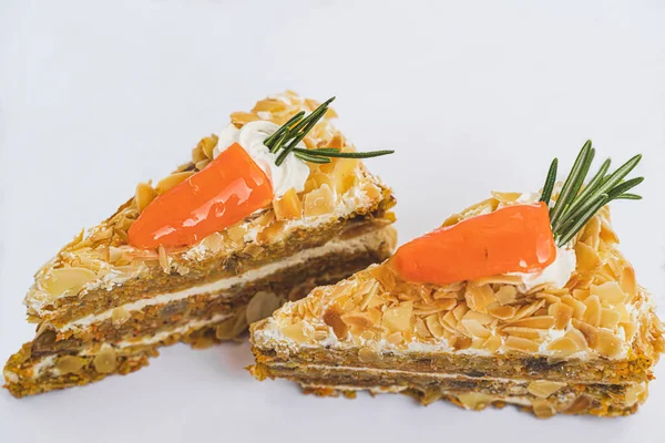 Two pieces of carrot cake dredged with flaked almonds and decorated with natural carrot on white background isolated and close up. Natural candy concept