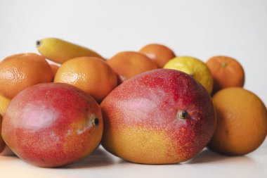 Mango ve narenciyenin durgun yaşamı beyaz arka planda, izole edilmiş. Meyveler lezzetli görünüyor ve özellikle kışın dopamin dolu oluyorlar. Doğal ürünler ve sağlıklı gıda konsepti, makro