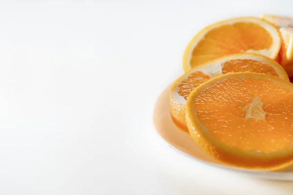 Beyaz arka plandaki tabakta lezzetli portakallı meyve dilimleri, yakın plan. Kopyalama alanı olan renkli resim.