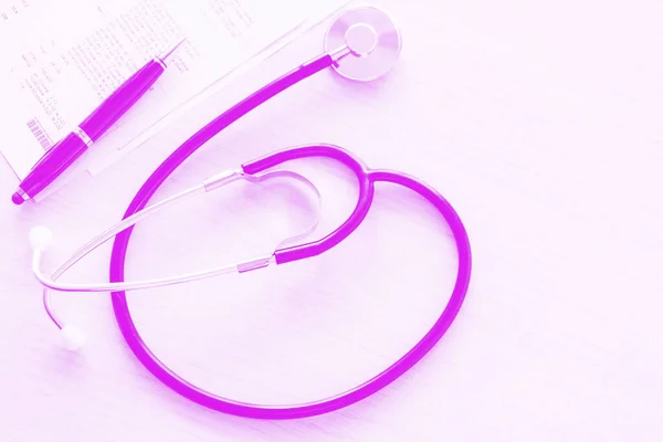Doktor masasının steteskop ve test sonuçları pembe arka planda, yakın plan ve üst görüş. Sağlık hizmeti kavramı.