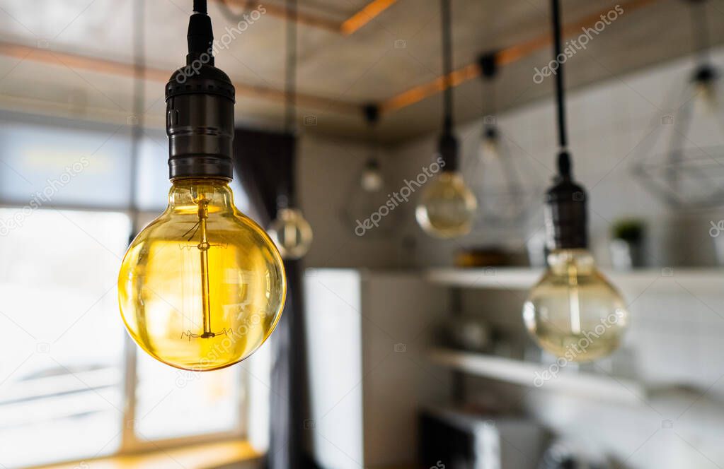 Close-up of incandescent light bulbs hanging in modern kitchen. Decorative antique edison light bulbs with straight wire. Inefficient filament light bulbs waste electricity. Warm white, dimmable, E27