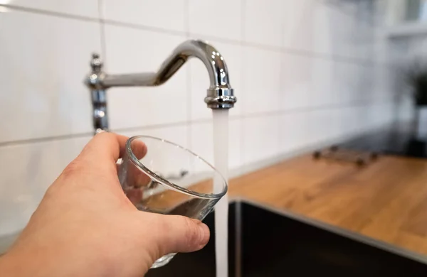 Man Hand Holding Empty Glass Nearby Stainless Steel Kitchen Tap — стоковое фото