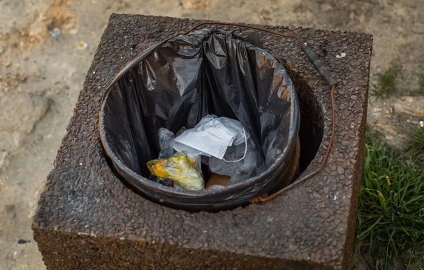 The end of coronavirus. Stop Covid 19. People discard surgical protective face mask in a public trash bin. Dirty used medical mask laying in a contaminated waste bin or garbage can during an epidemic
