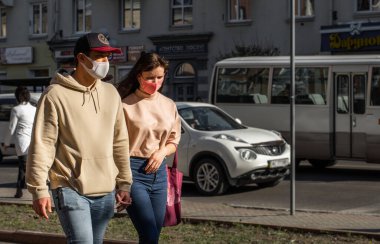 Lutsk, Ukrayna - 20 Nisan 2020: Genç çift Coronavirus salgınının ortasında bir sokakta maske takıyor. Şehirdeki bulaşıcı hastalıklar sırasında sağlık koruma ve virüs salgınını önleme