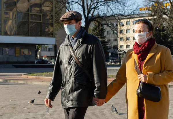 Lutsk, Ukrayna - 20 Nisan 2020: Genç çift Coronavirus salgınının ortasında bir sokakta maske takıyor. Şehirdeki bulaşıcı hastalıklar sırasında sağlık koruma ve virüs salgınını önleme