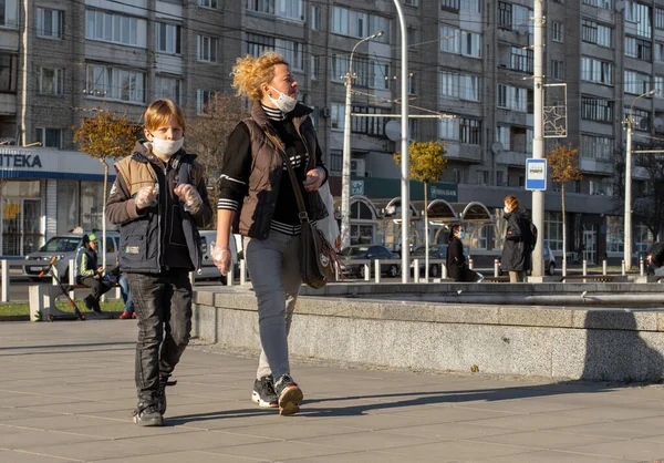 Lutsk, Ukrayna - 20 Nisan 2020: Anne ve çocuk koronavirüs salgınının ortasında halka açık bir sokakta yüz maskesi takıyor. Şehirdeki bulaşıcı hastalıklar sırasında sağlık koruma ve virüs salgınını önleme