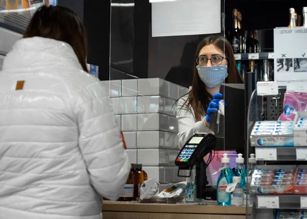 Lutsk, Ukrayna - 10 Mayıs 2020: Avrupalı kadın süpermarket kasiyeri pleksiglas kalkanların arkasındaki bakkalda çalışıyor. Marketlerde Coronavirus önlemi. Alışveriş.
