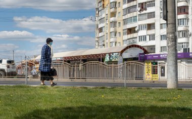 Lutsk, Ukrayna - 20 Mayıs 2020: Büyükannem koronavirüs salgınının ortasında halka açık bir sokakta yüz maskesi takıyordu. Şehirdeki bulaşıcı hastalıklar sırasında sağlık koruma ve virüs salgınını önleme