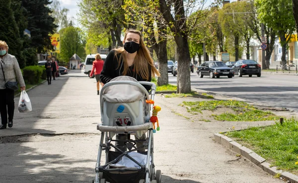 Lutsk, Ukrayna - 20 Mayıs 2020: Coronavirus salgınının ortasında halk sokaklarında yüz maskesi takan bir kadın. Şehirdeki bulaşıcı hastalıklar sırasında sağlık koruma ve virüs salgınını önleme