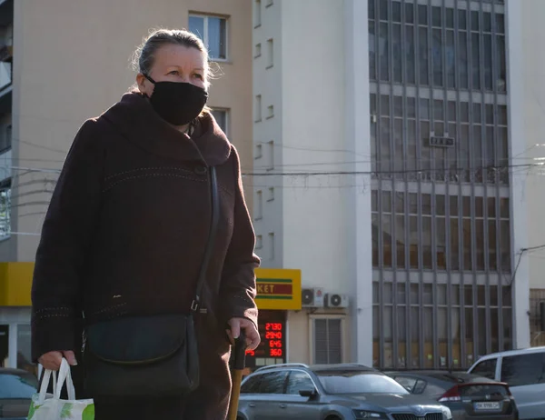 Lutsk, Ukrayna - 20 Mayıs 2020: Büyükannem koronavirüs salgınının ortasında halka açık bir sokakta yüz maskesi takıyordu. Şehirdeki bulaşıcı hastalıklar sırasında sağlık koruma ve virüs salgınını önleme