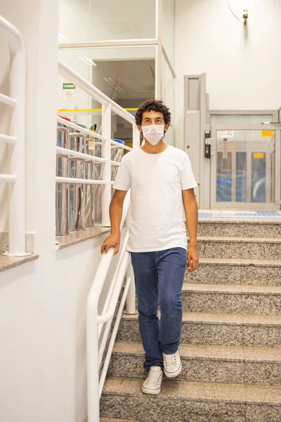 22-year-old man with protective mask, leaning close to a handrail