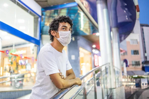 22-year-old man with protective mask, leaning close to a handrail