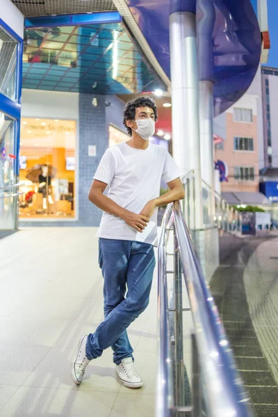 22-year-old man with protective mask, leaning close to a handrail
